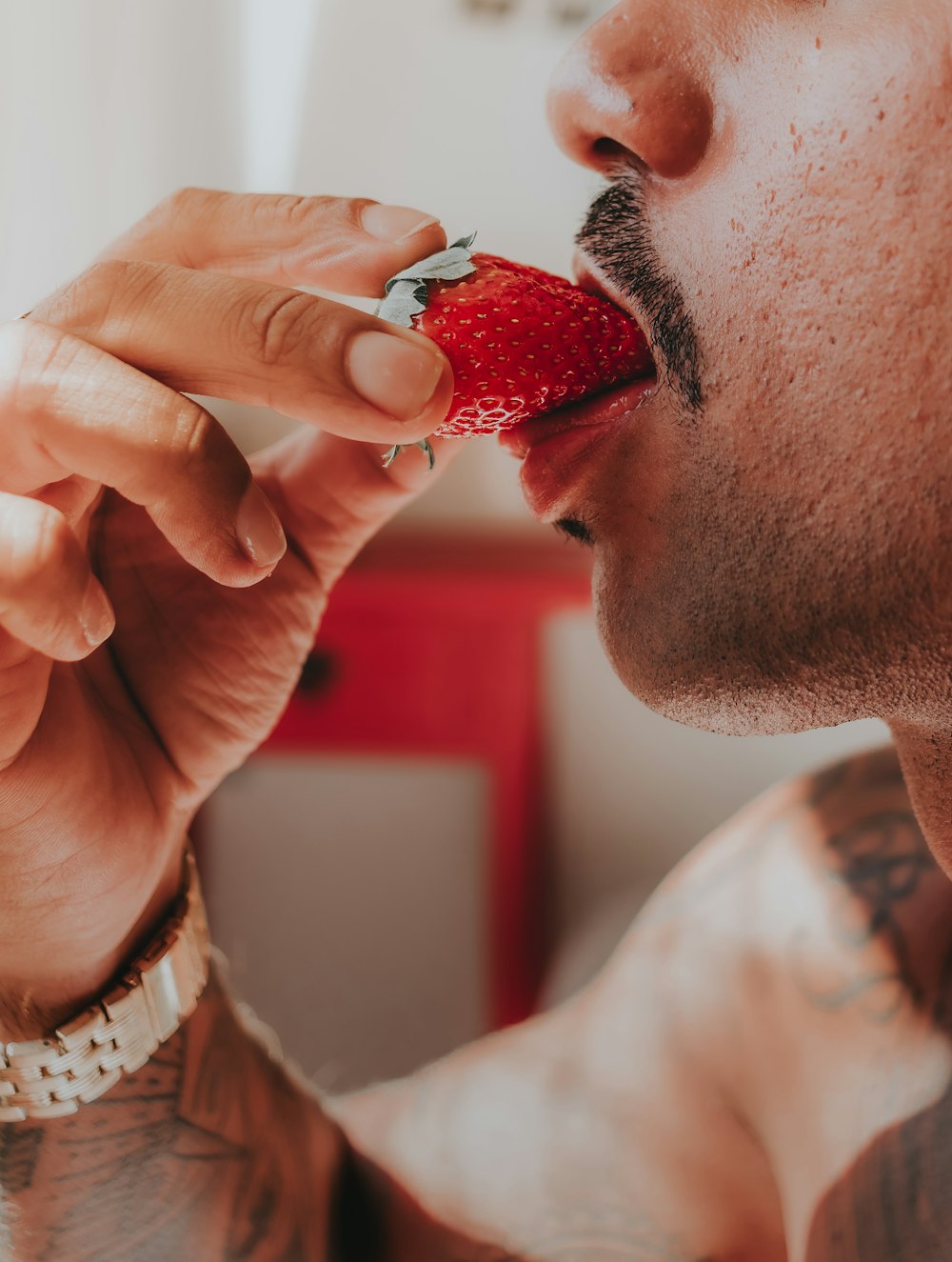 man in white shirt holding strawberry