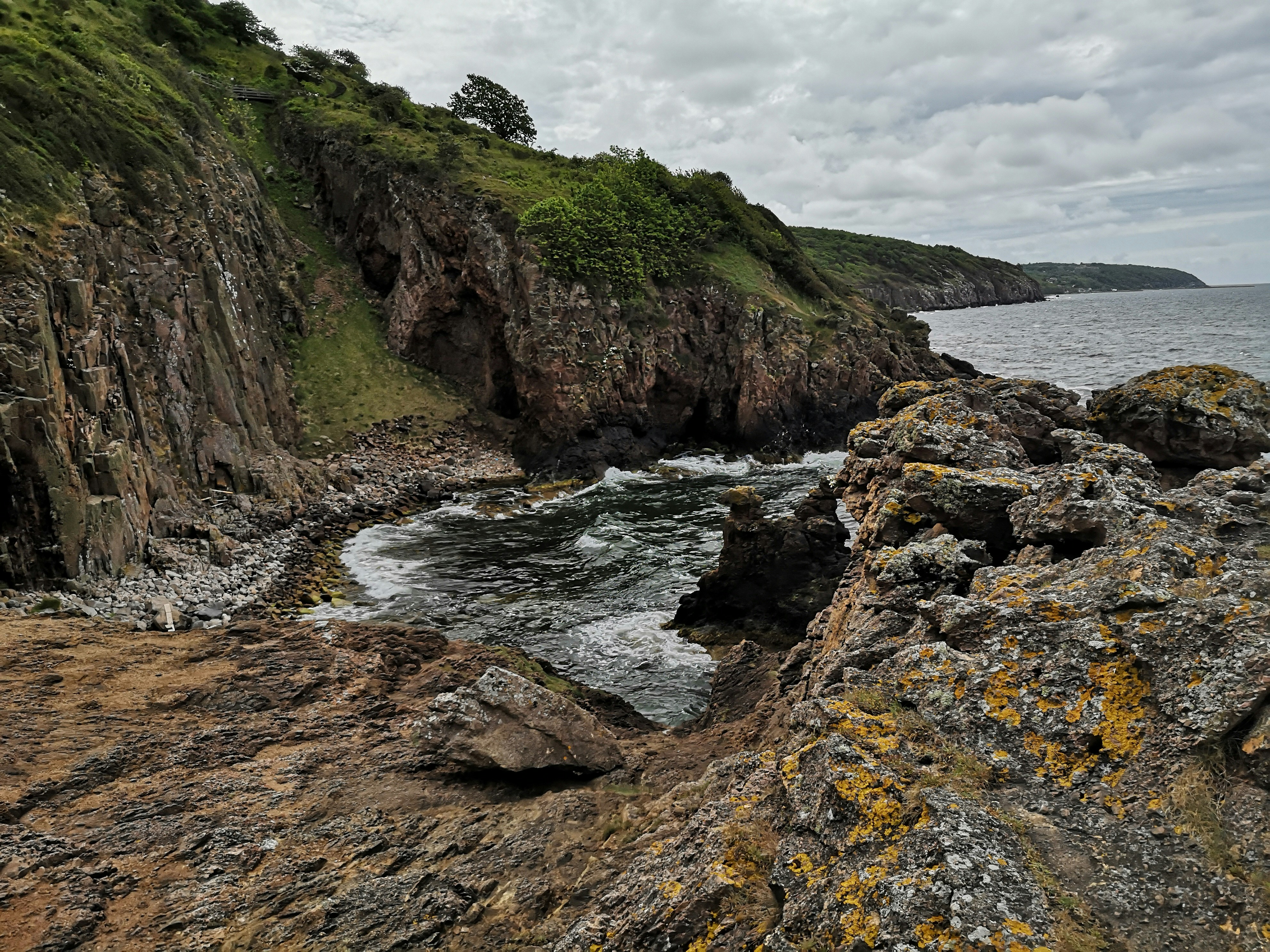 green and brown rock formation near body of water during daytime