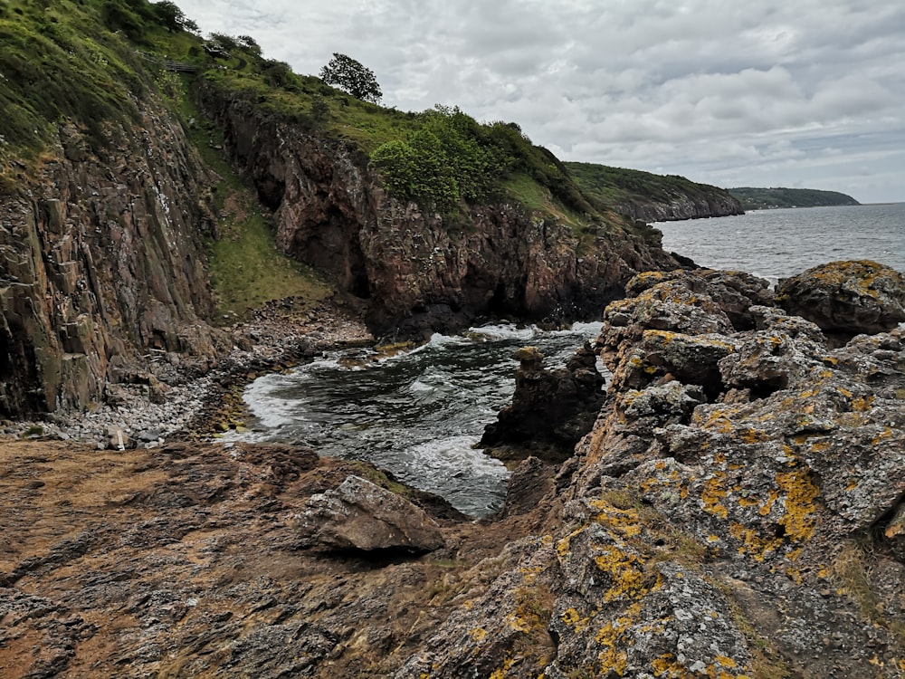 green and brown rock formation near body of water during daytime