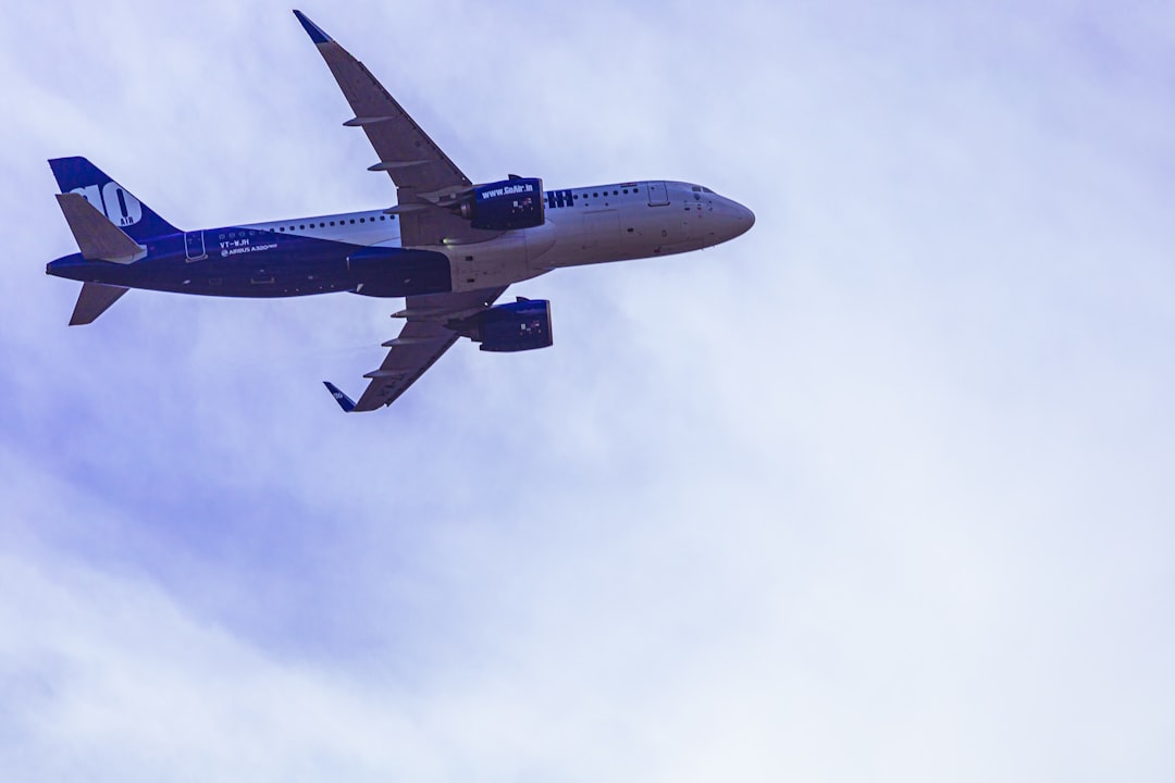 white and blue airplane under white clouds during daytime