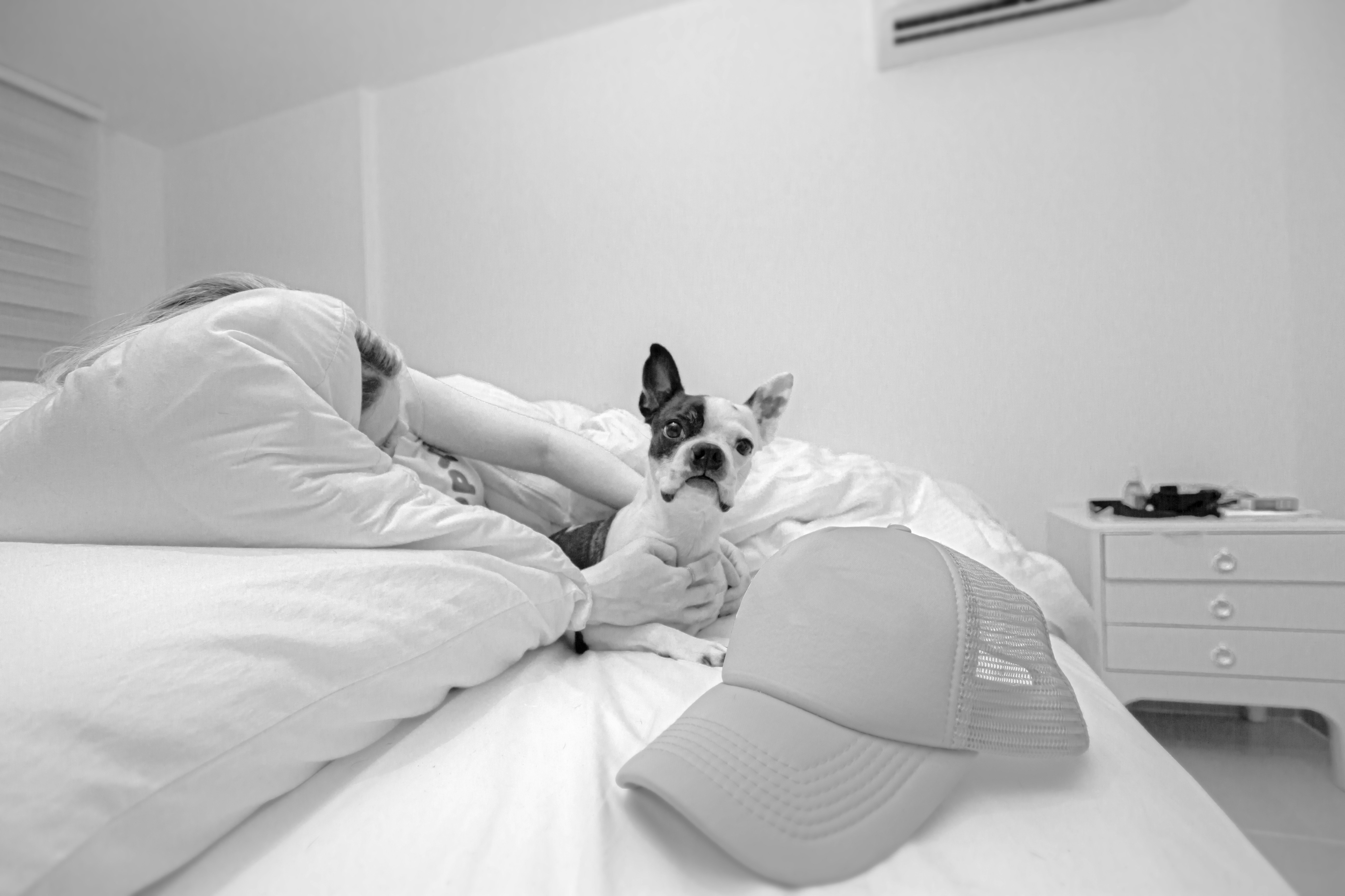 Grayscale photo of woman lying on bed beside dog