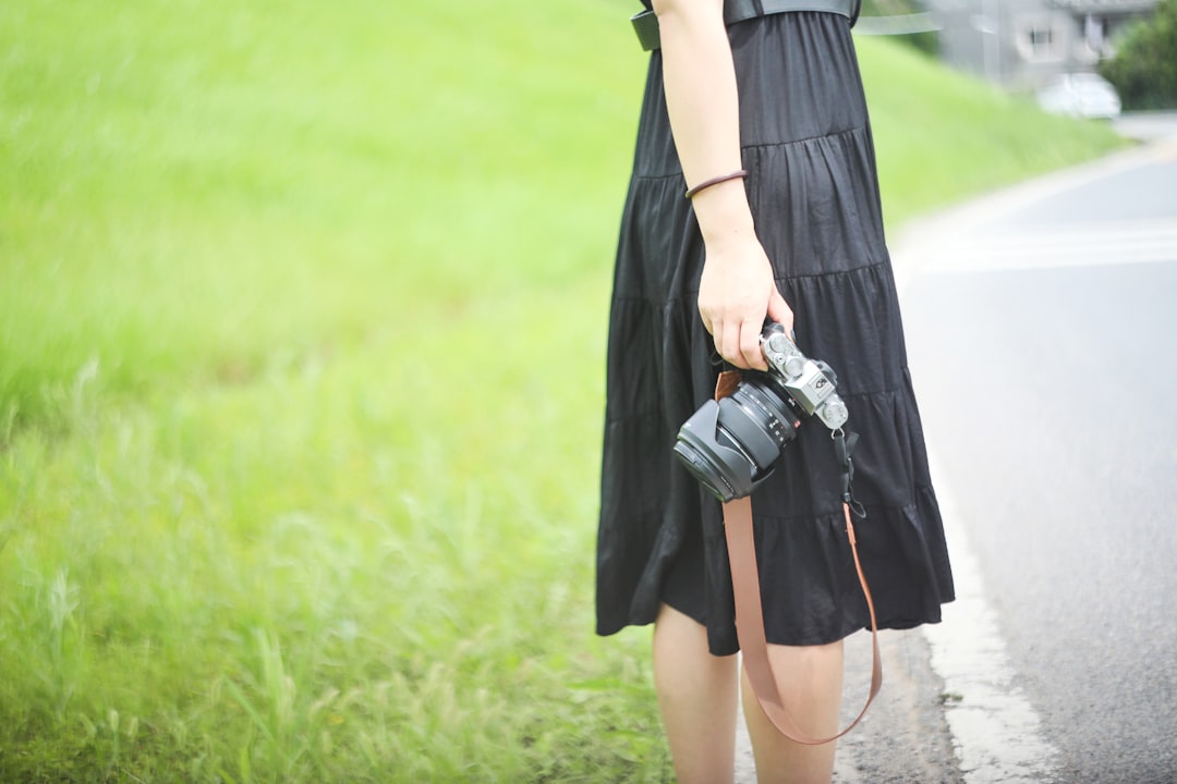 woman in black dress holding black dslr camera