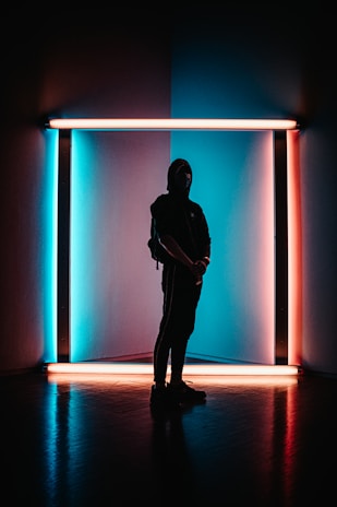 A shadowy figure illuminated by cool blue neon, capturing the mood beneath the city's glow.