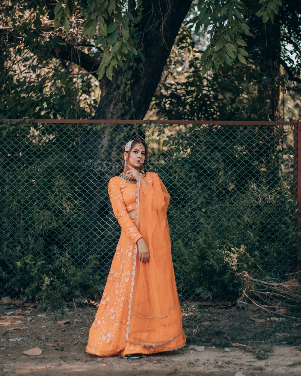 woman in brown dress standing beside black metal fence