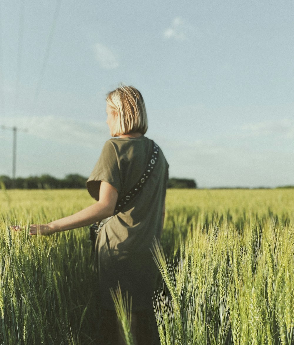 mulher na camiseta preta que está de pé no campo verde da grama durante o dia