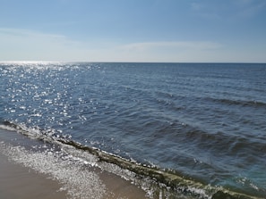 A serene shoreline with sea glass sparkling under a clear blue sky