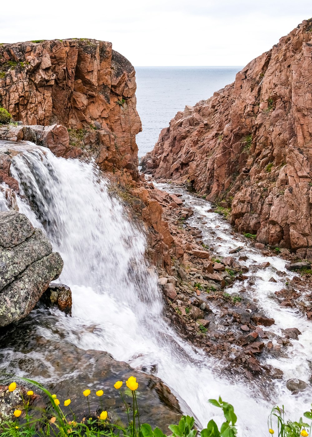 water falls between brown rocky mountain during daytime