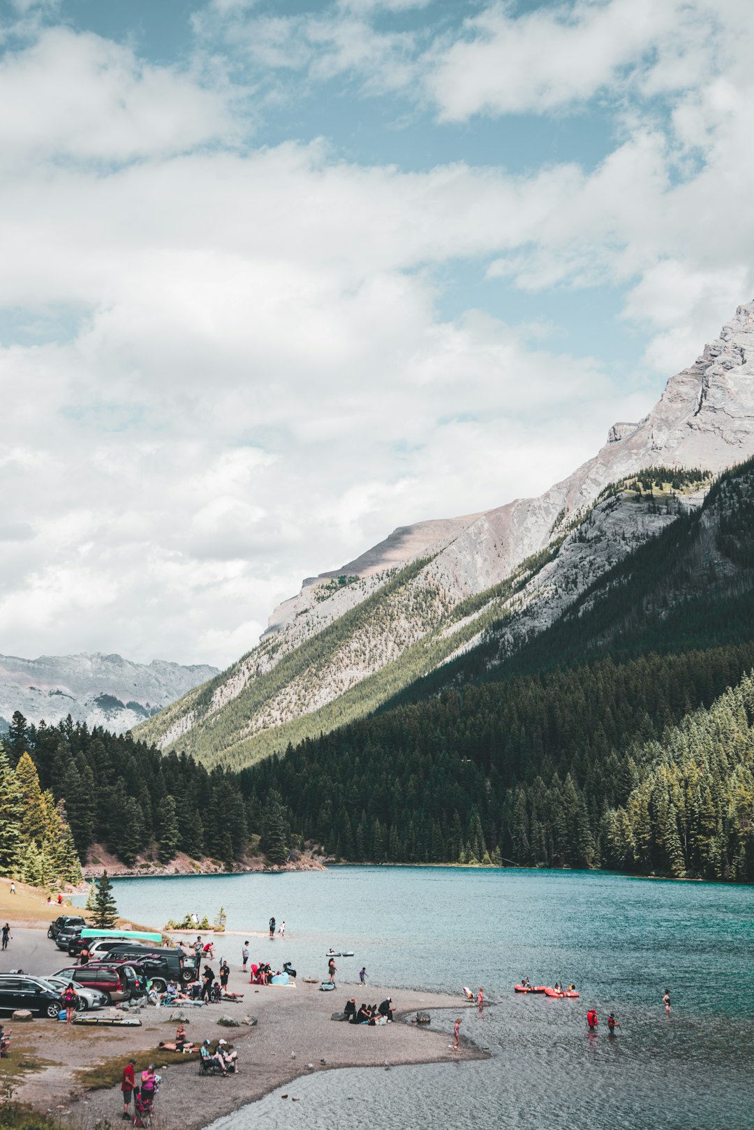 green trees near body of water and mountain under white clouds during daytime