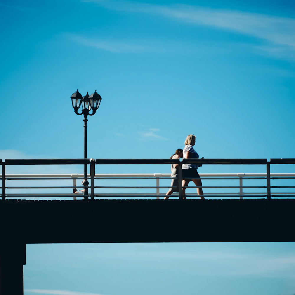 Femme en chemise blanche et pantalon noir debout sur des balustrades en métal noir pendant la journée