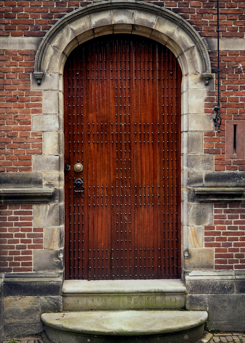 灰色のコンクリートレンガの壁に茶色の木製のドア