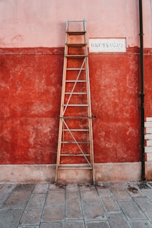 red metal ladder leaning on red wall