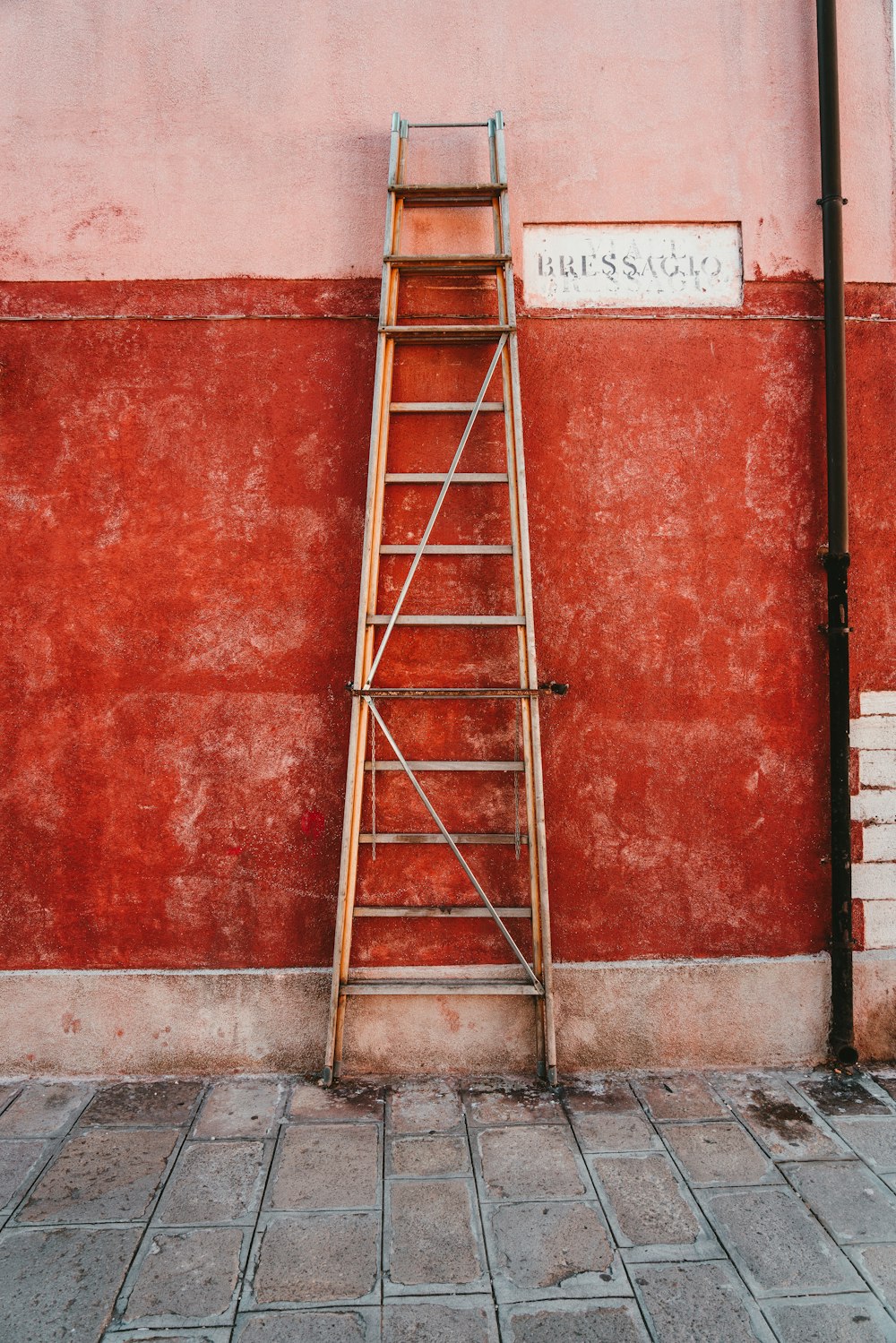 赤い壁に寄りかかる赤い金属製の梯子