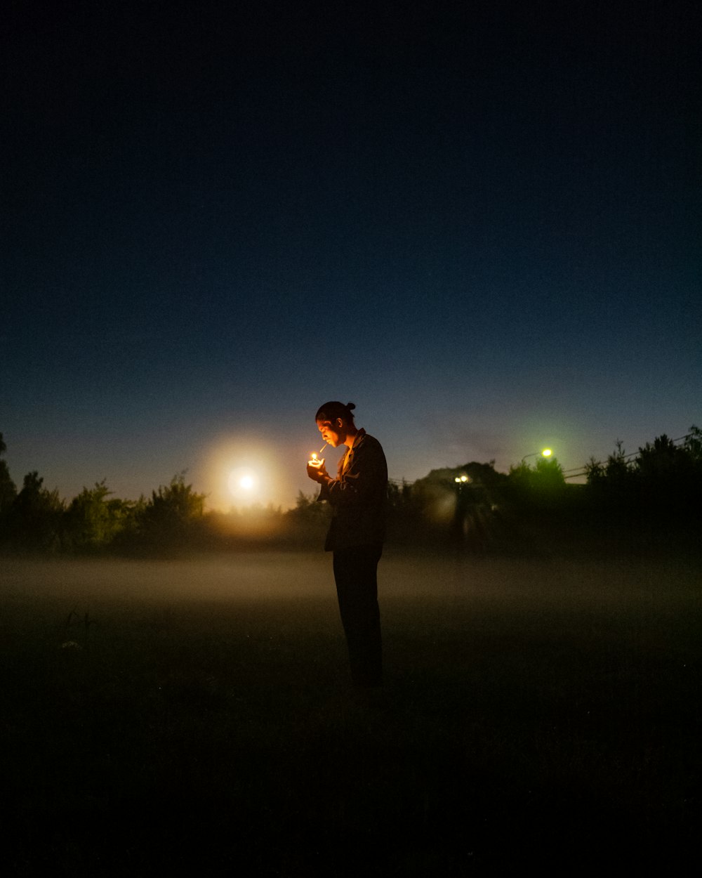man in black jacket standing on green grass field during night time