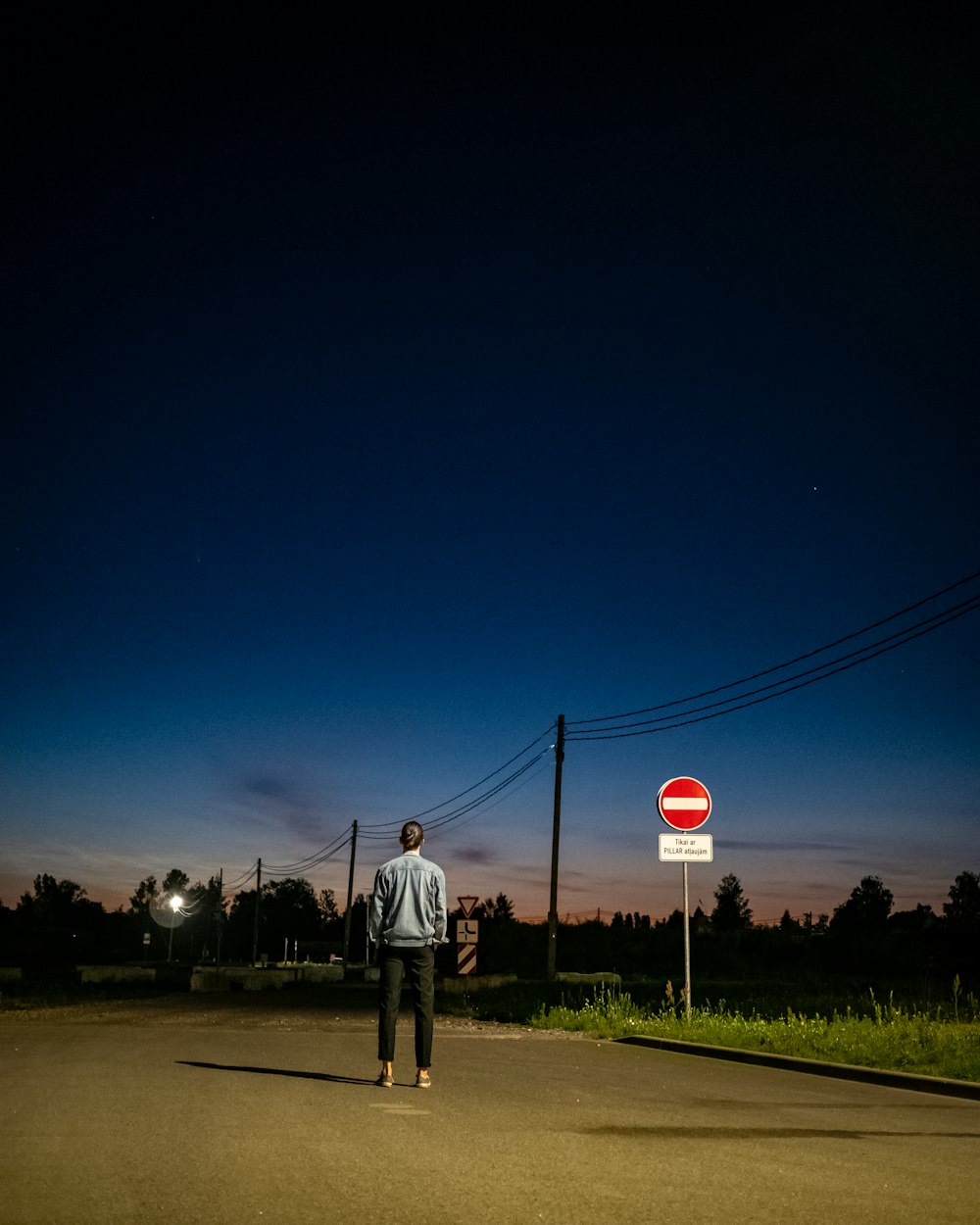 man in white shirt standing on the street during night time