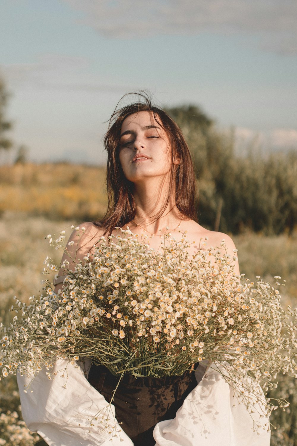 woman in white floral dress holding white flowers