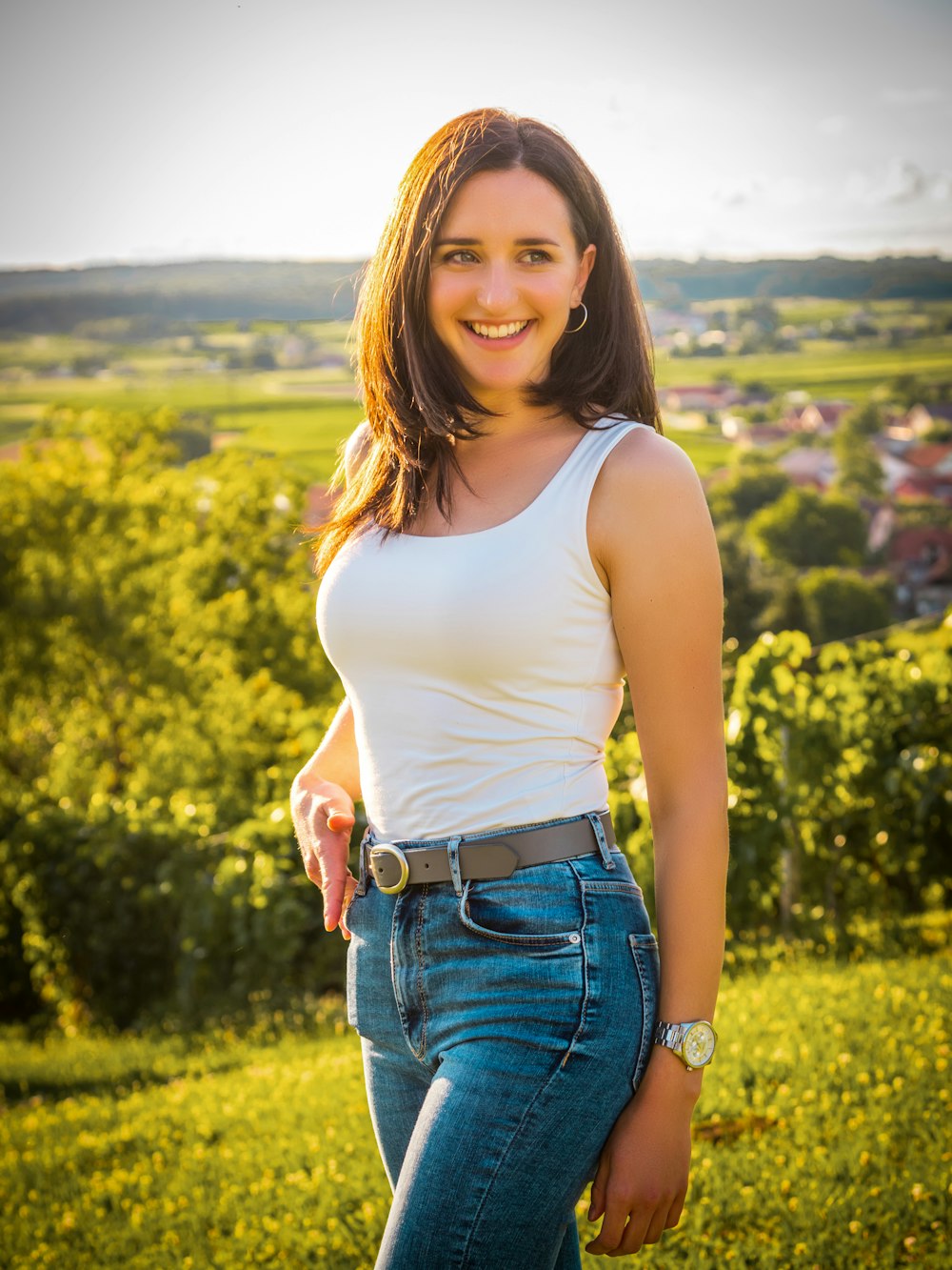 woman in white tank top and blue denim shorts standing on green grass field during daytime