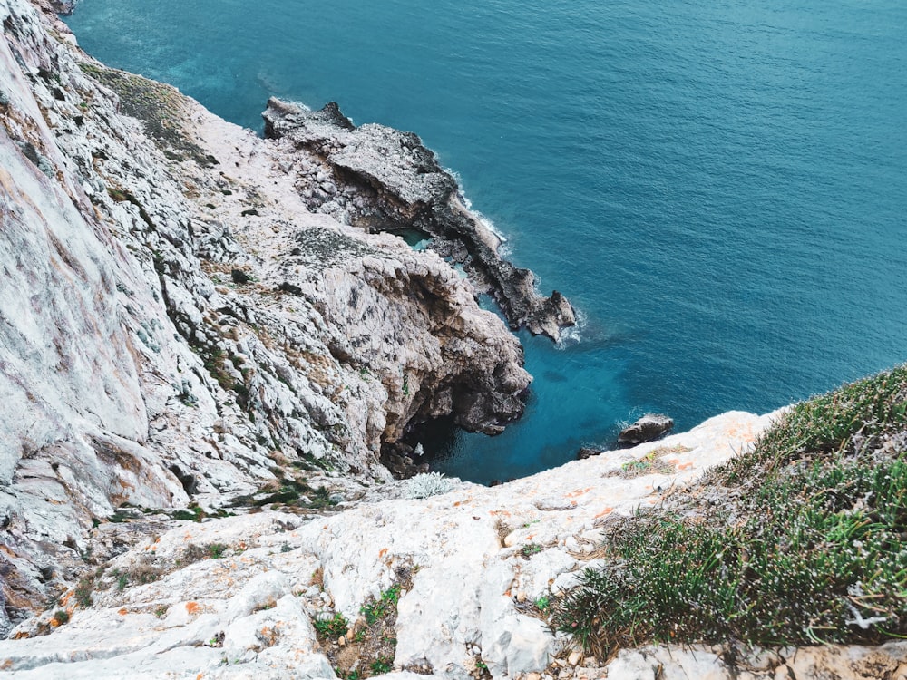 gray rocky mountain beside blue sea during daytime