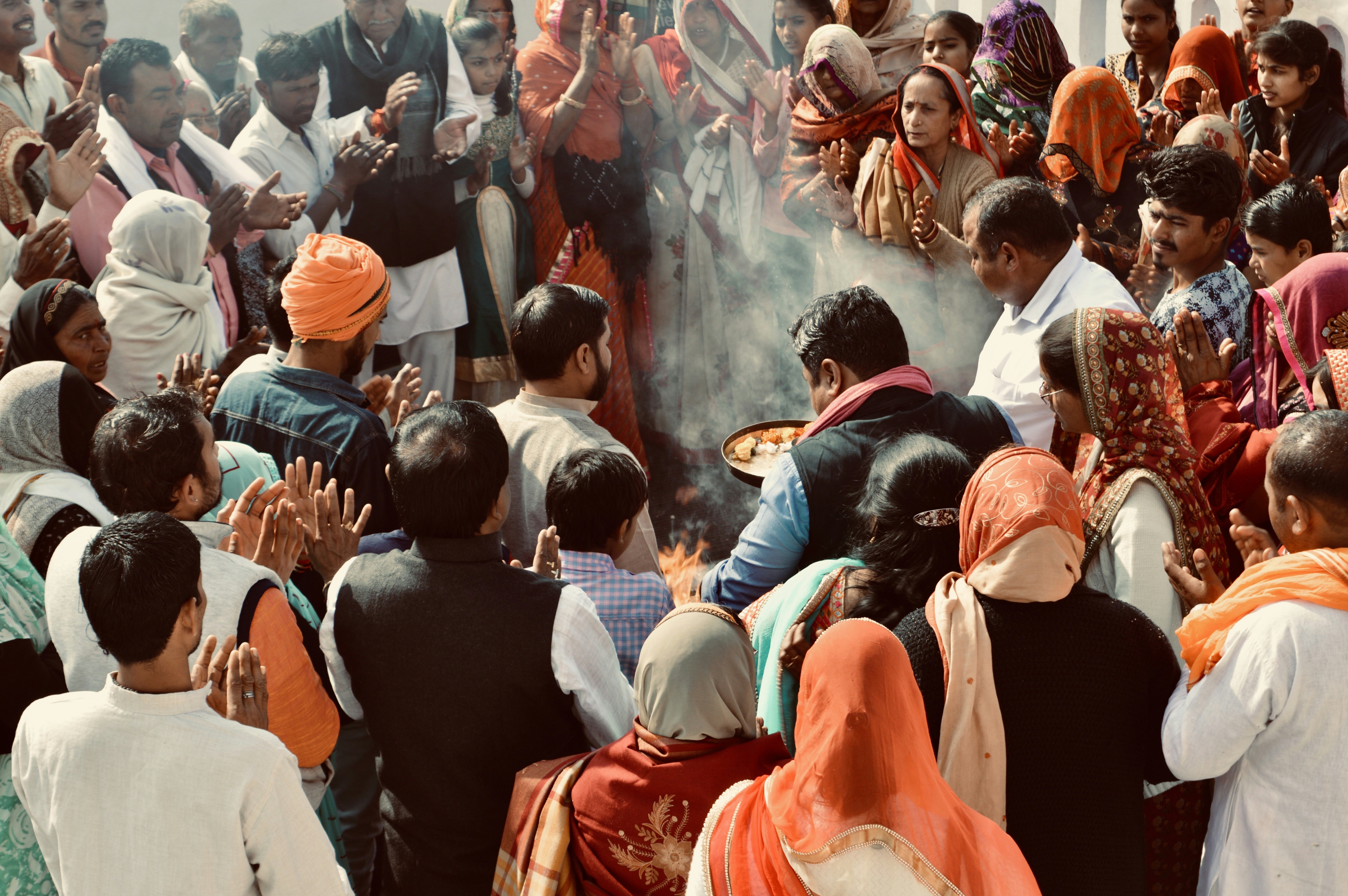 A wider shot showing the crowd outside the Eidgah, with both Hindu and Muslim individuals mingling peacefully, perhaps some engaging in conversations or greetings.