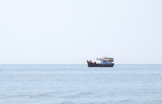 A fishing boat at sea with a clear blue sky and calm waves.