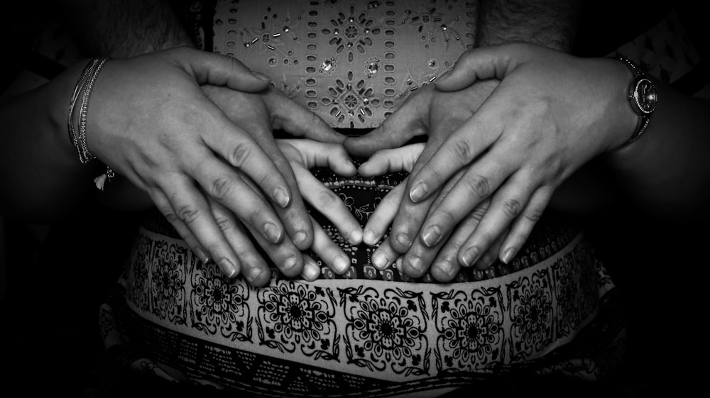 grayscale photo of persons hand on top of floral textile