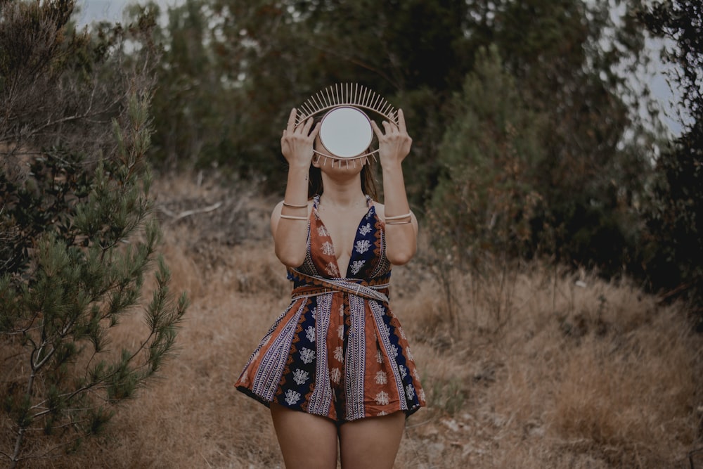 woman in black and red floral dress holding white hat