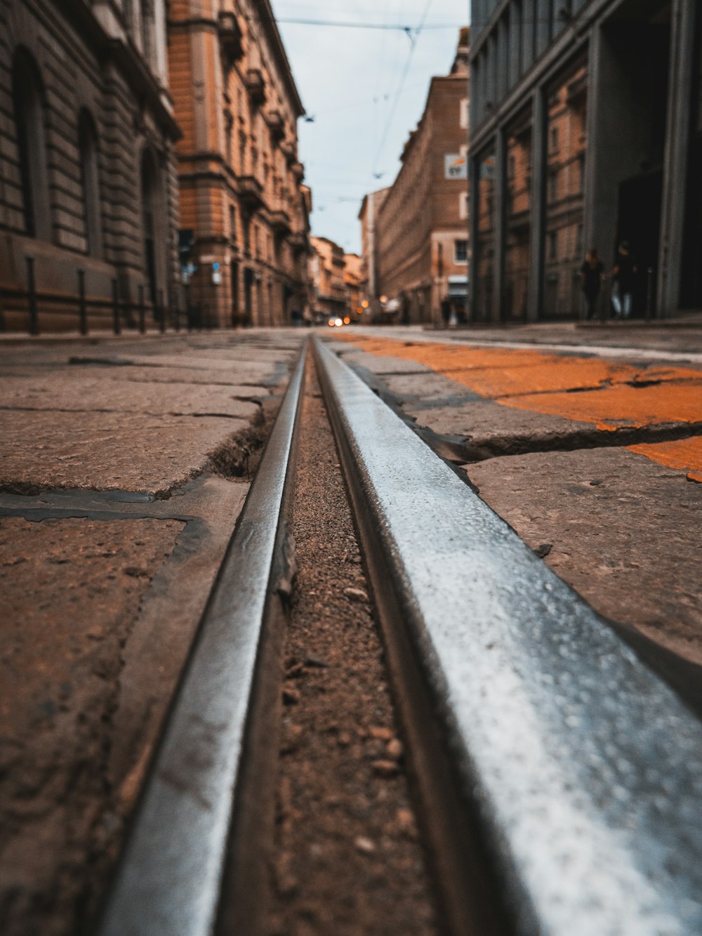 Carril de tren marrón y blanco entre edificios de ladrillo marrón durante el día