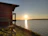 Sunset view over a peaceful lakeside cabin with natural beige and green surroundings