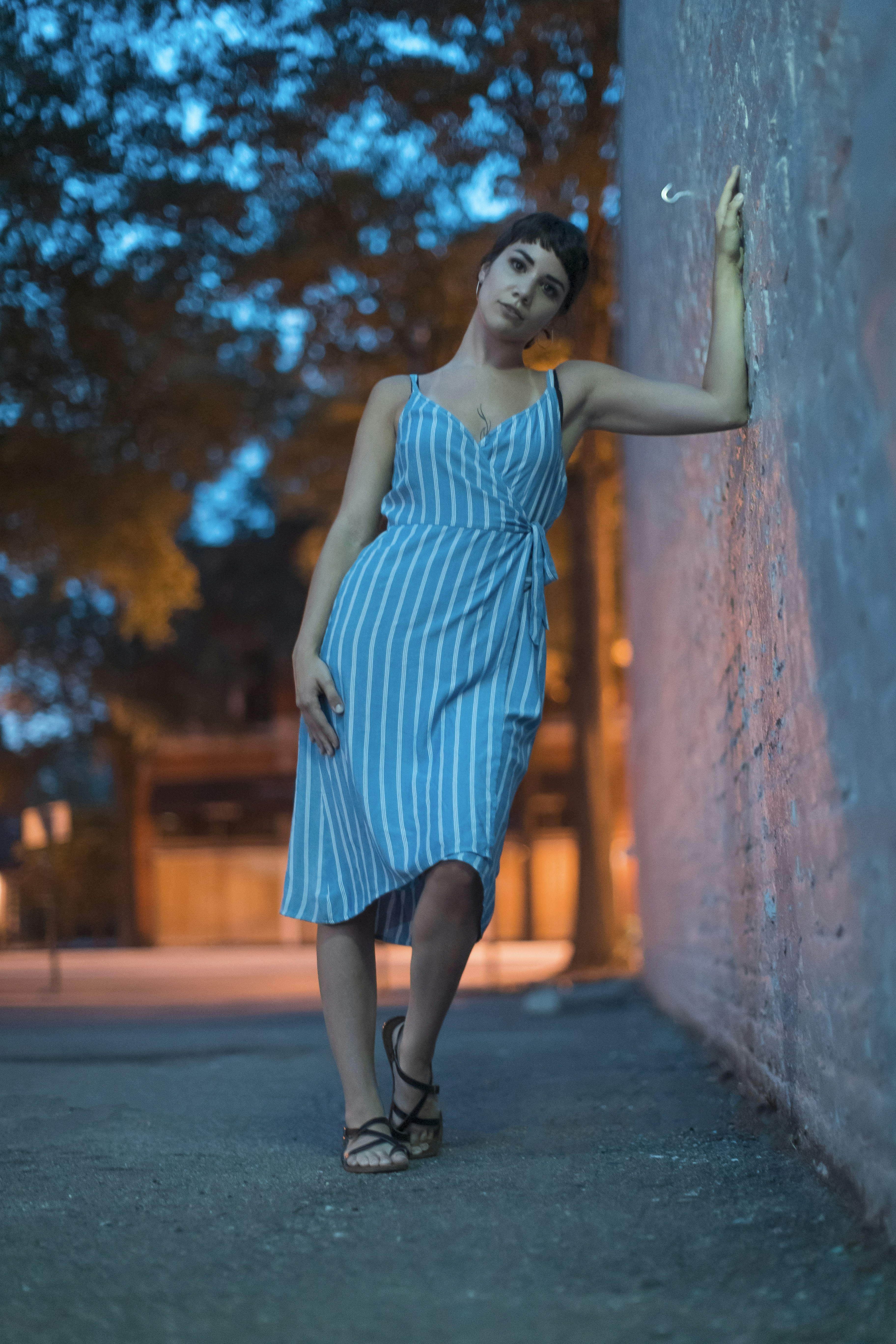 woman in blue sleeveless dress standing on sidewalk during daytime