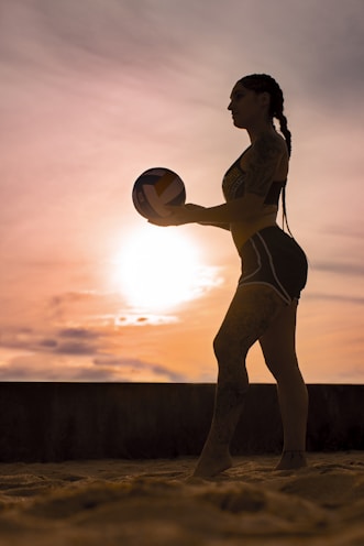 woman in white bikini holding yellow ball during sunset
