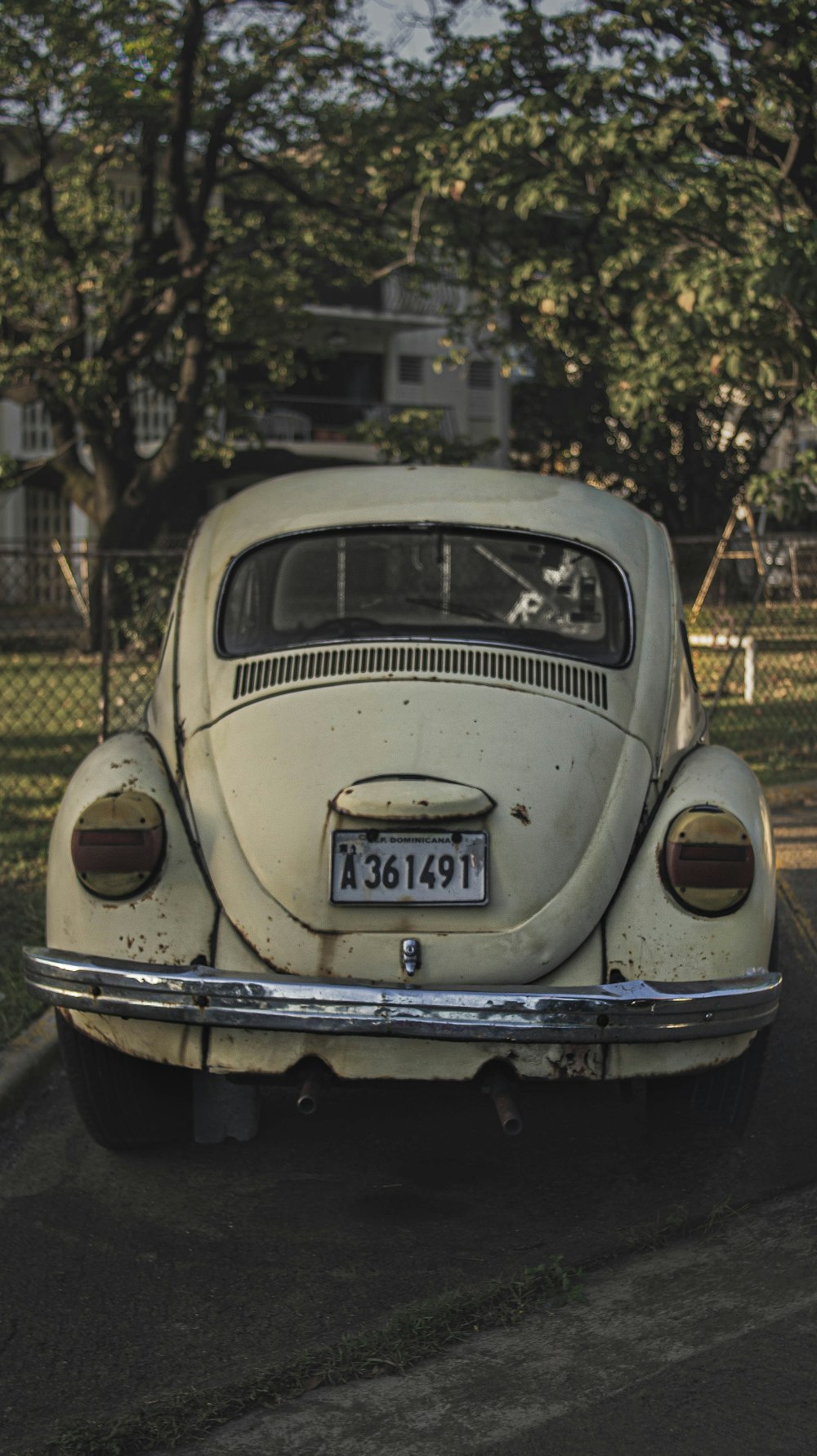 white classic car parked near white metal fence during daytime