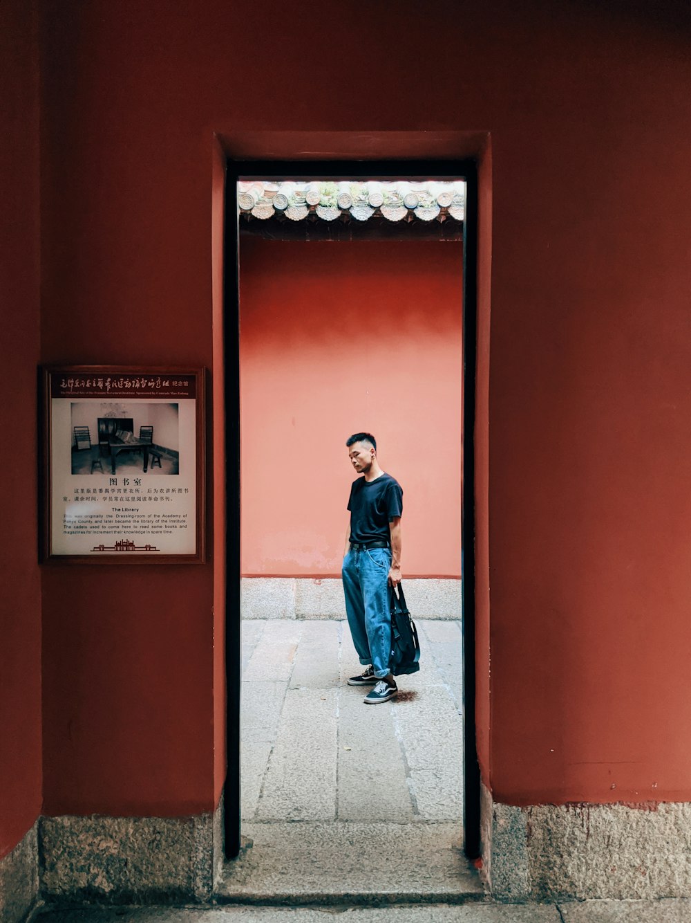 man in blue denim jacket standing in front of red door