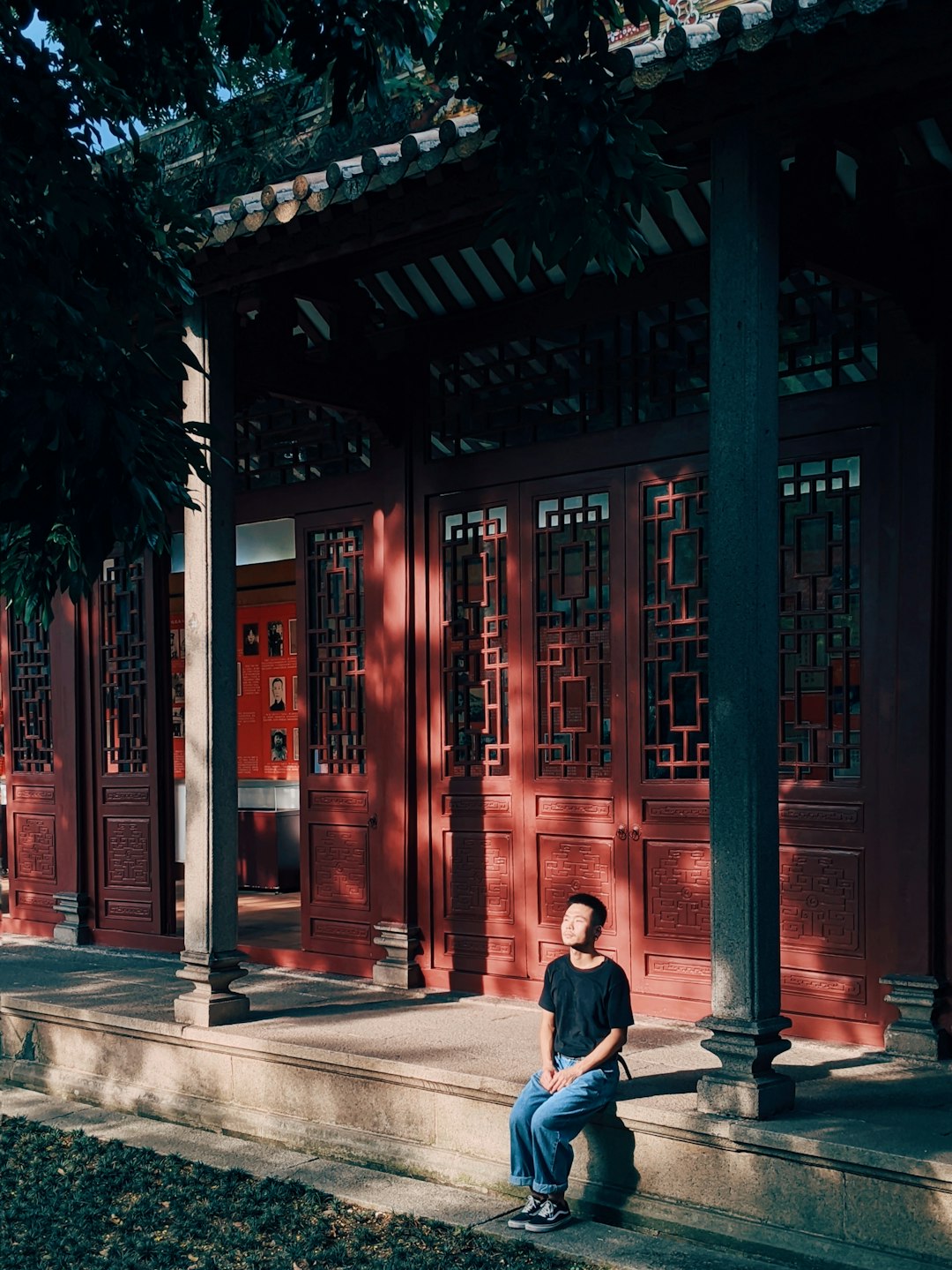 woman in black jacket and blue denim jeans sitting on sidewalk during daytime