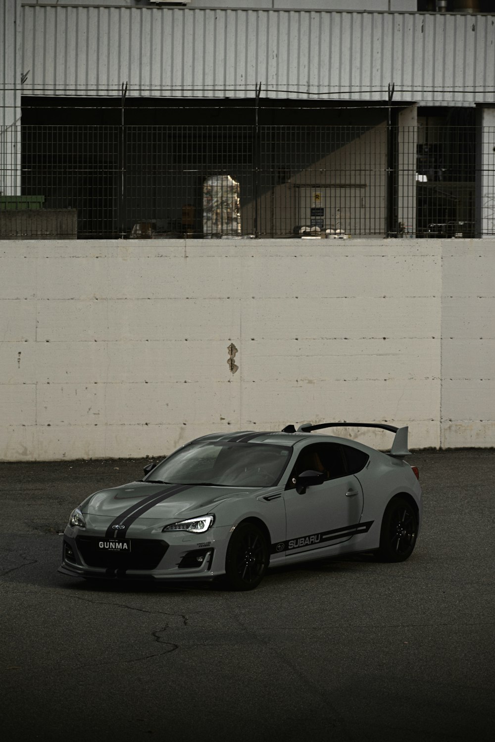 gray porsche 911 parked beside white wall