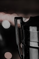 A close-up of a trophy handle with a blurred, bokeh-lit background featuring circular light patterns. The metallic surface of the handle and part of the trophy is visible, reflecting some of the light.