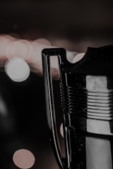 A close-up of a trophy handle with a blurred, bokeh-lit background featuring circular light patterns. The metallic surface of the handle and part of the trophy is visible, reflecting some of the light.