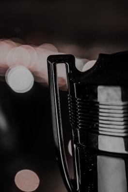 A close-up of a trophy handle with a blurred, bokeh-lit background featuring circular light patterns. The metallic surface of the handle and part of the trophy is visible, reflecting some of the light.