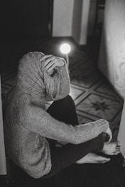 person in gray sweater holding lighted candle