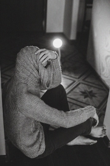 person in gray sweater holding lighted candle
