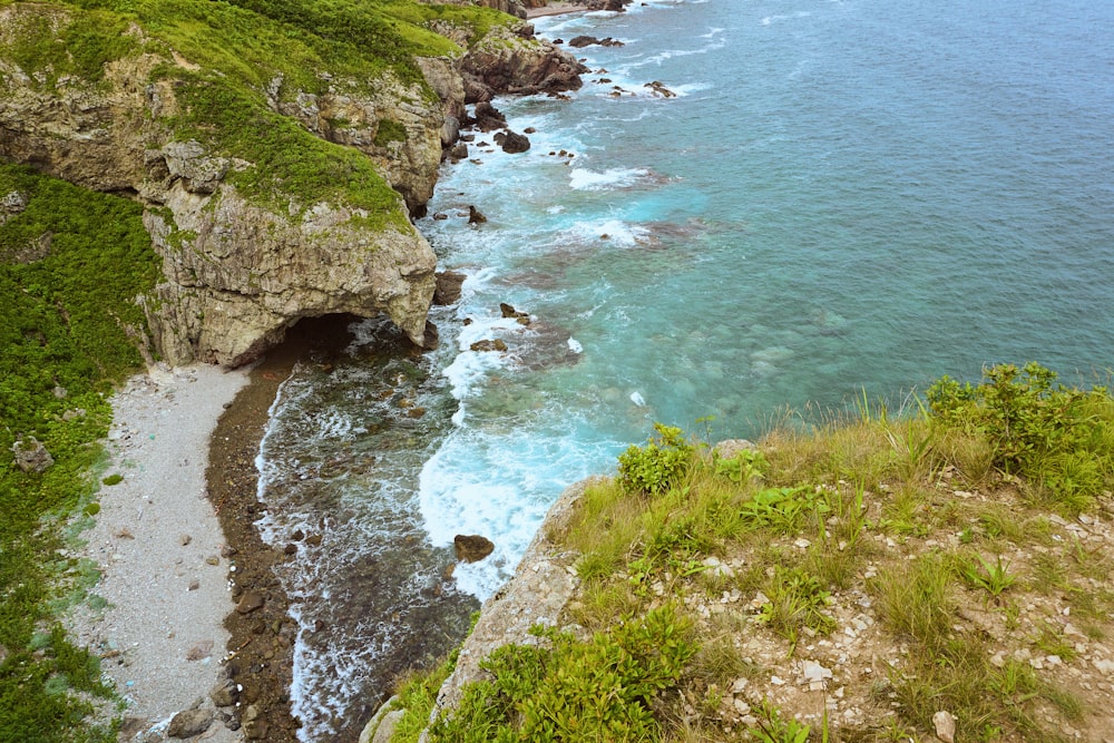 green grass covered mountain beside sea during daytime