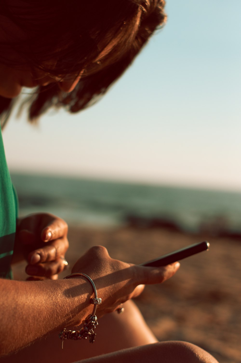 woman in green shirt holding smartphone during daytime