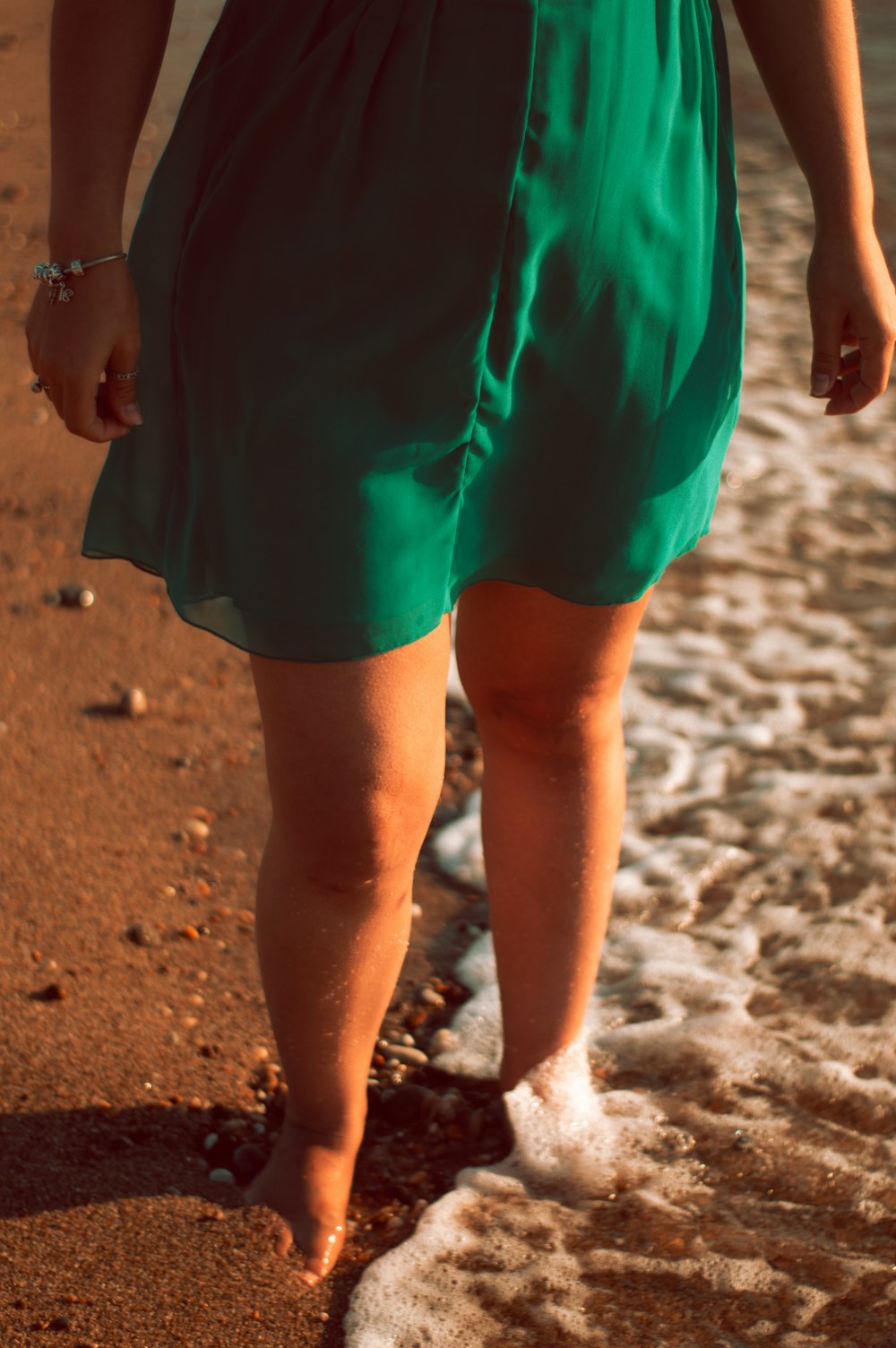 woman in green skirt walking on beach during daytime