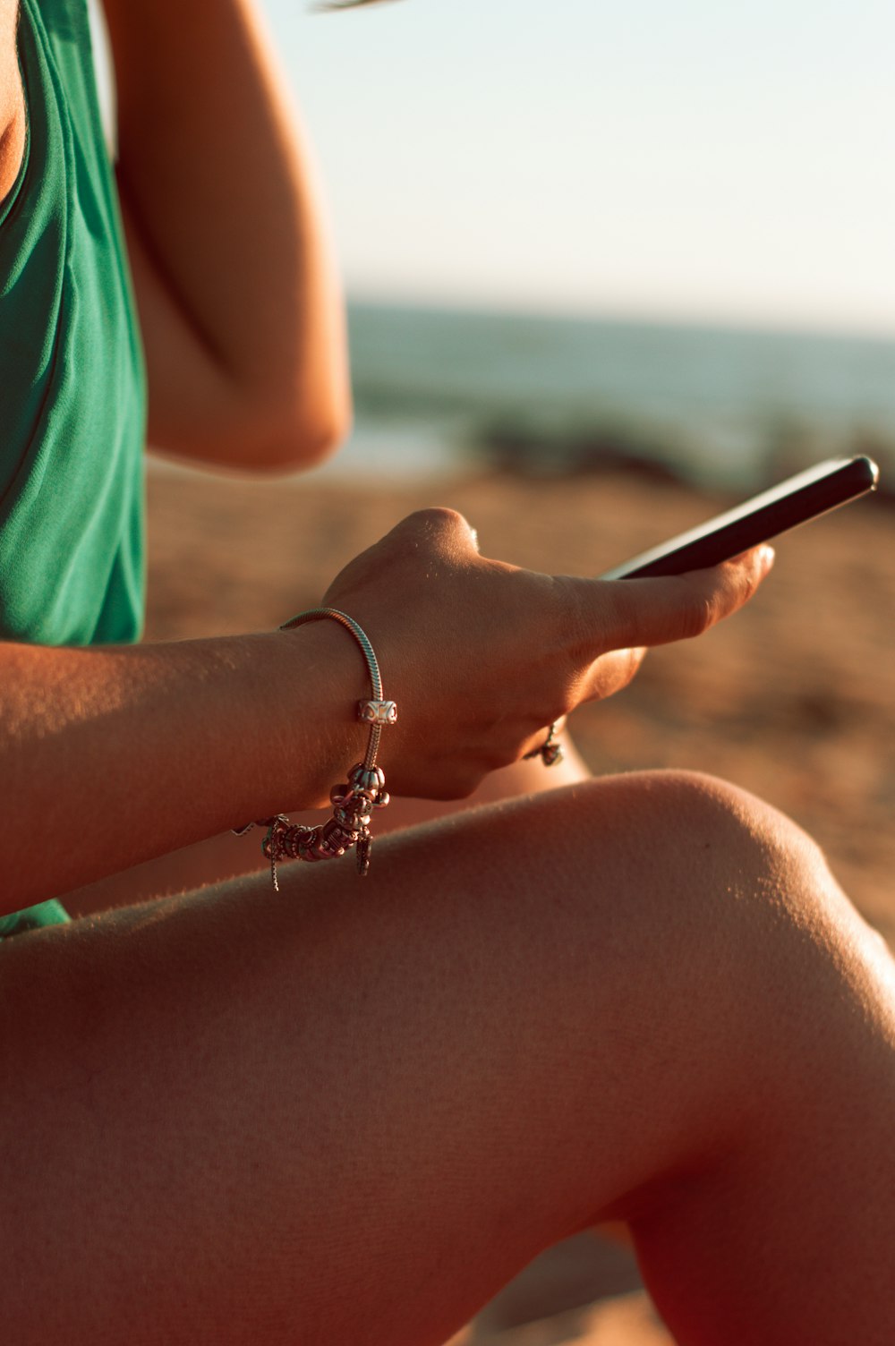 woman in green shirt holding black smartphone