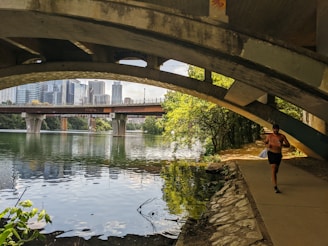 A scenic sunrise view over a city skyline with a lone runner on a bridge.