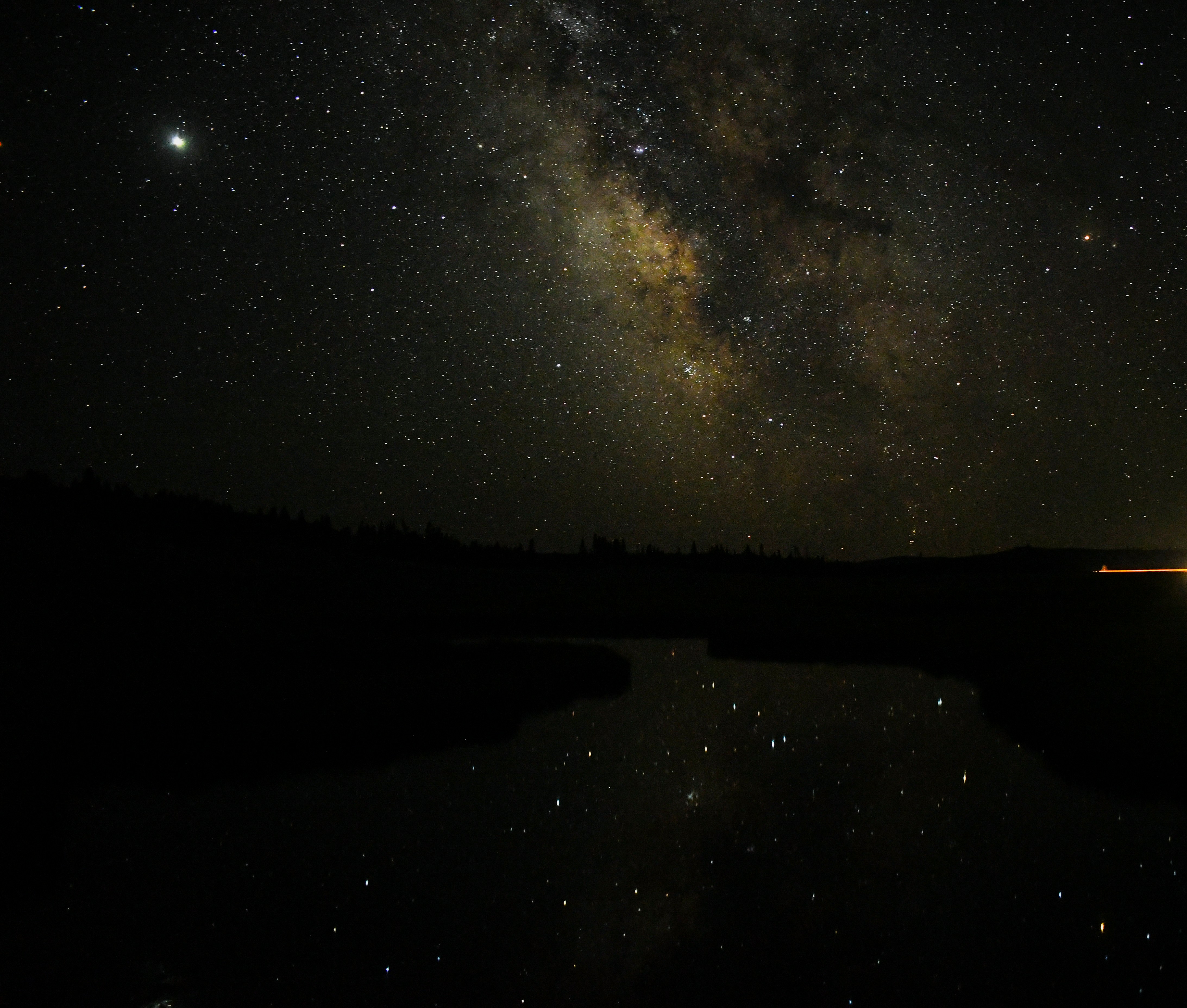 Night sky with milky way stars over dark silhouetted landscape, deep indigo and black, infinite and quiet