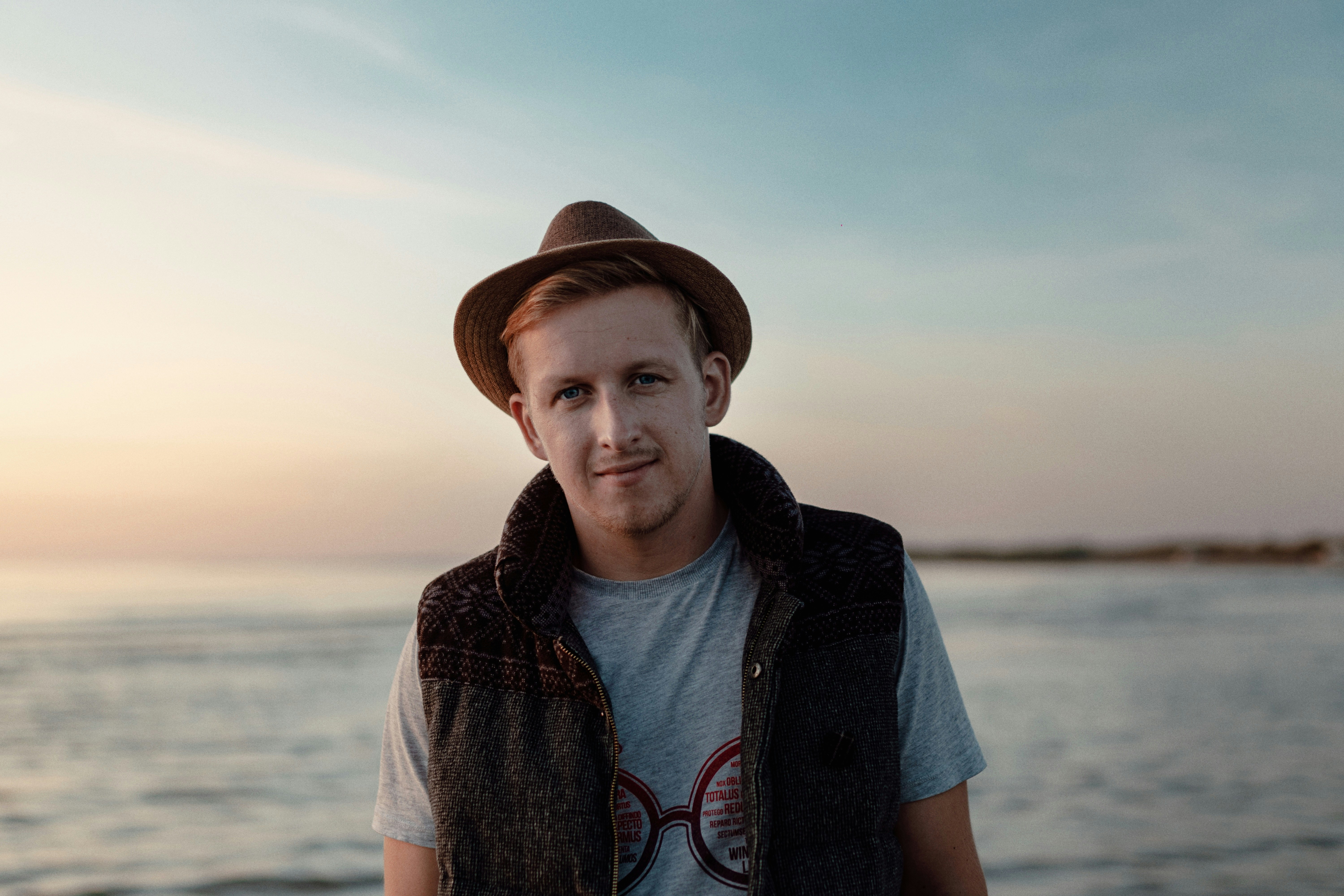 man in brown hat and blue denim jacket standing on beach during daytime
