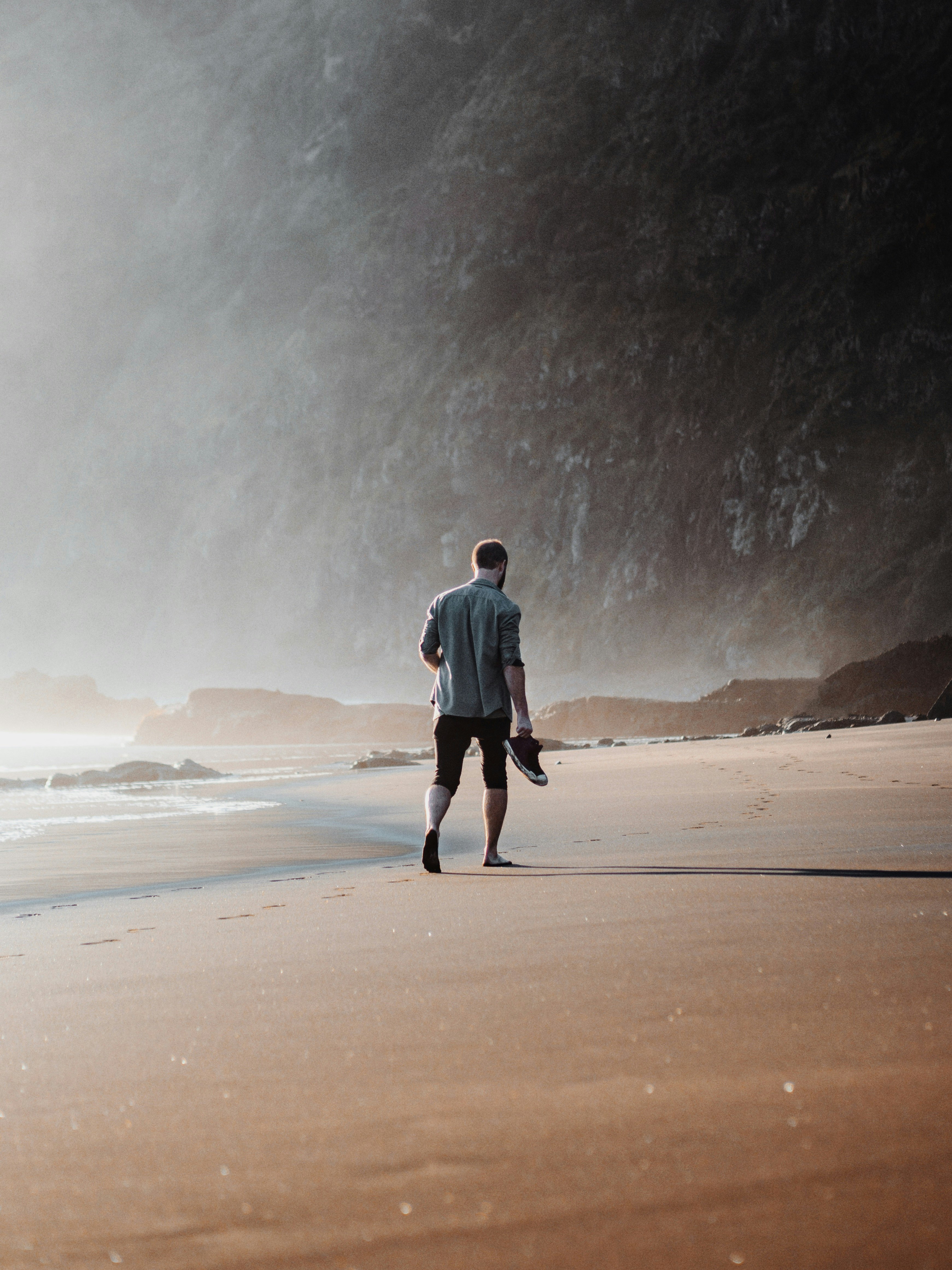 man in black jacket walking on brown sand during daytime