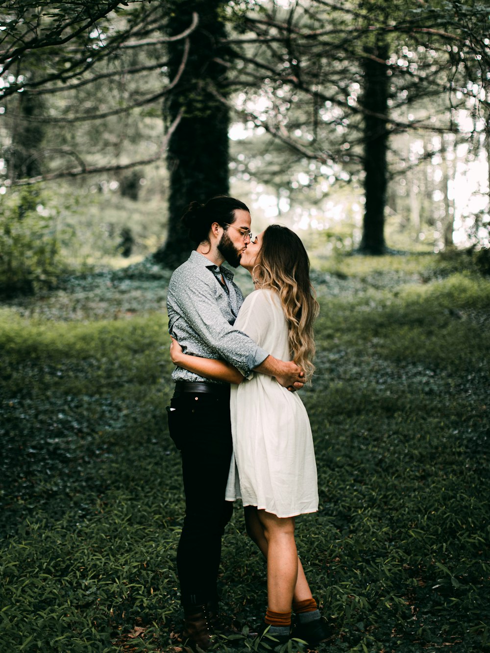 man and woman kissing on green grass field during daytime