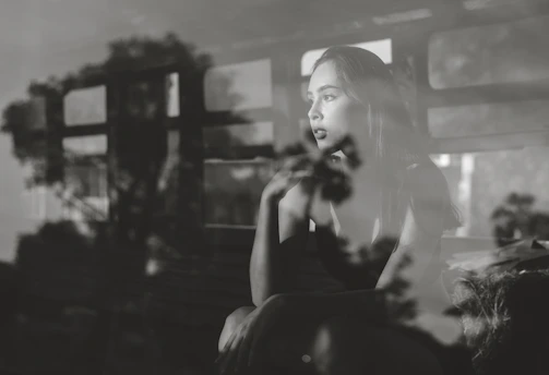 A thoughtful woman sitting by a window, reflecting on her emotions