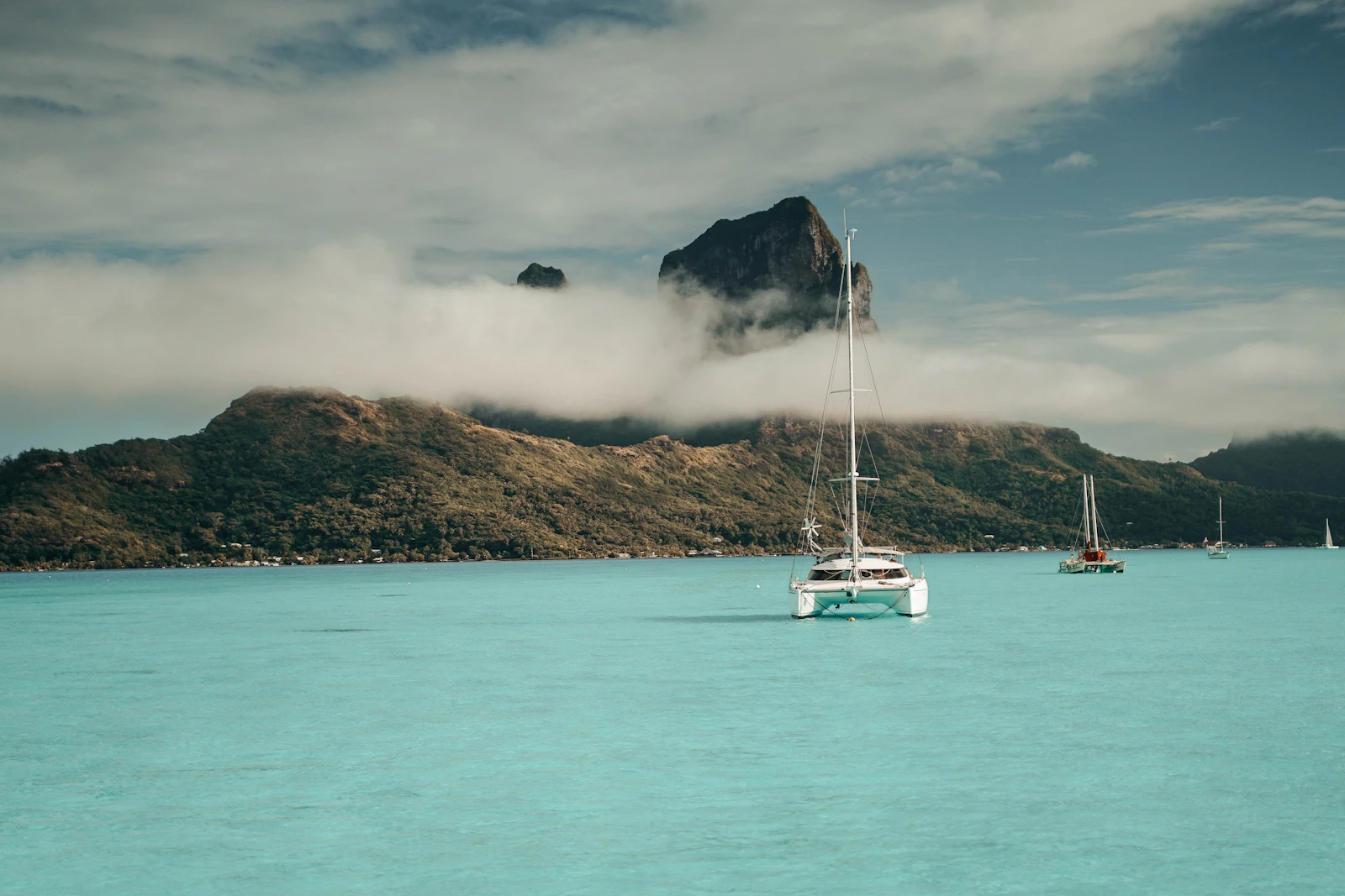 A white catamaran on the turquoise Bora Bora lagoon with Mount Otemanu behind