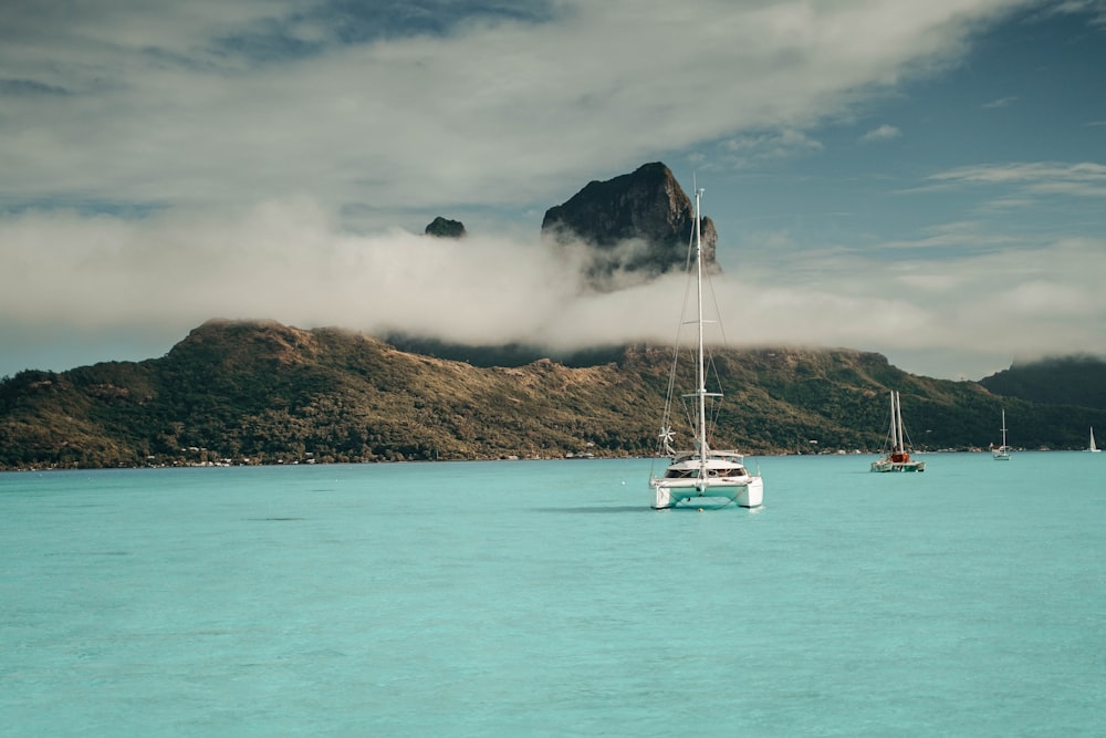 white boat on sea near mountain under white clouds during daytime